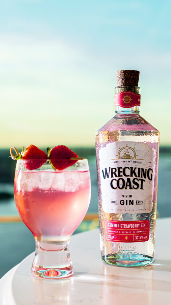 A bottle of Summer Strawberry Gin with a glass of Summer Strawberry Gin on a table