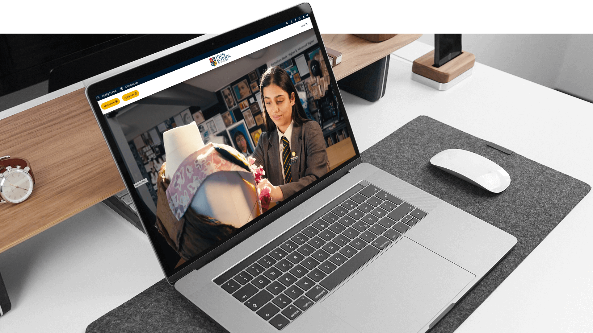 A laptop displaying High School of Dundee website with a pupil in a classroom.