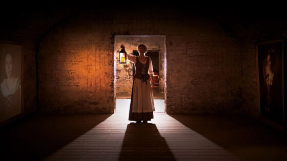 Continuum banner with a person standing in a door frame holding a candle light