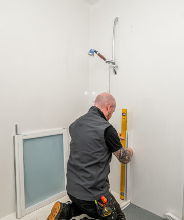 tradesperson measuring in a bathroom to fit a shower unit