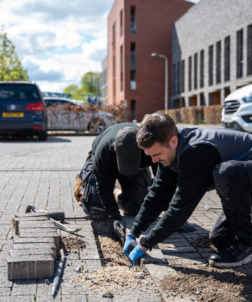 tradespeople fixing paving stones in parking area