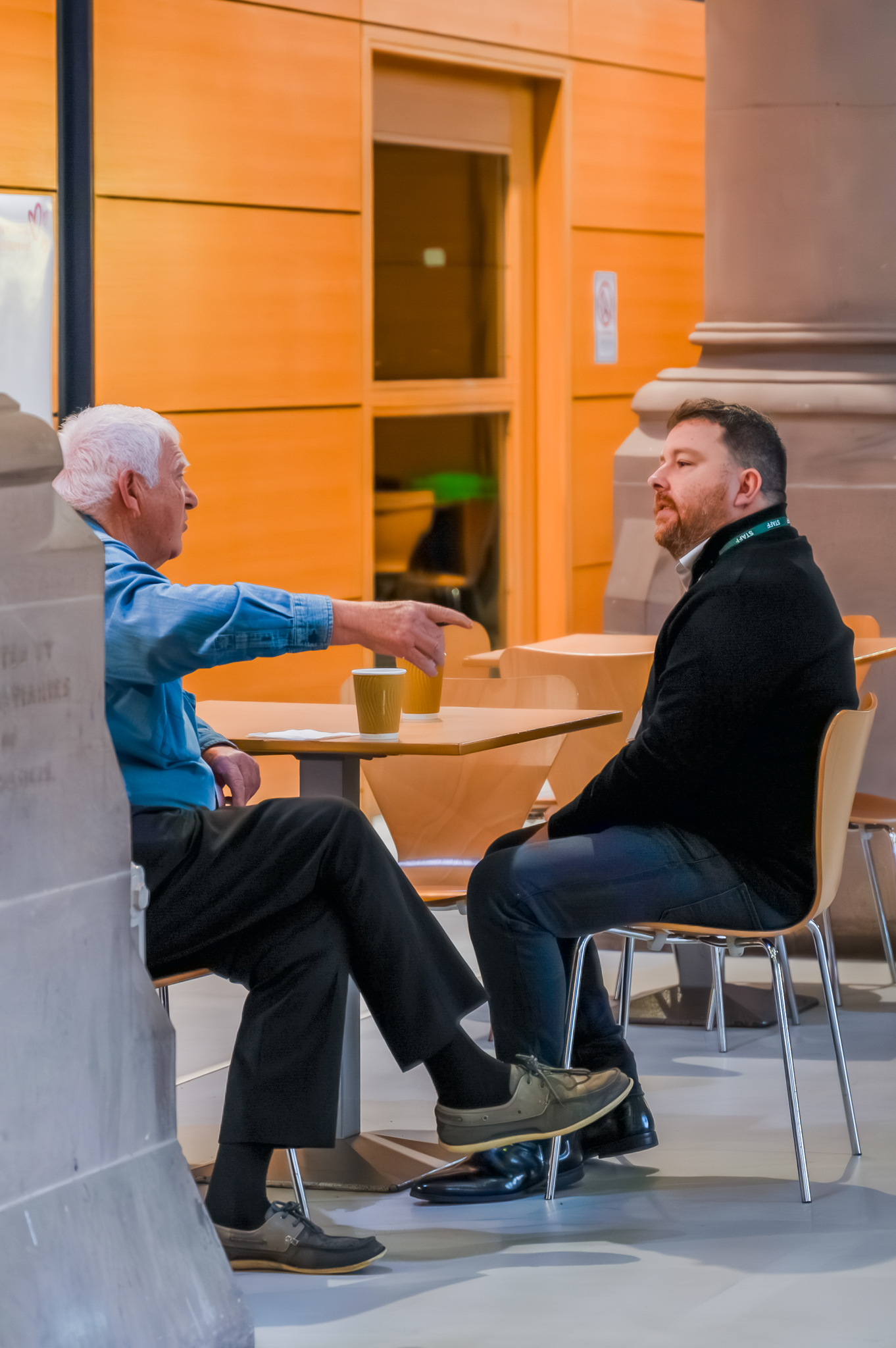 Two men sat at a small round table engaged in a discussion