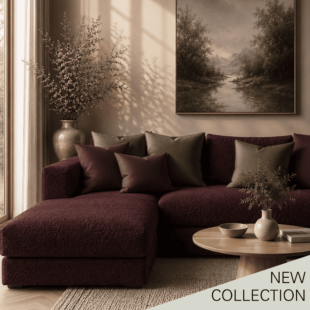 Elegant living room with a burgundy sectional sofa, decorative cushions, a framed landscape painting, and warm sunlight streaming through a tall window.