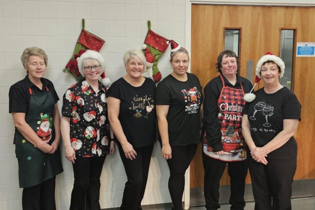 Six members of the catering team in festive outfits posing in a line.