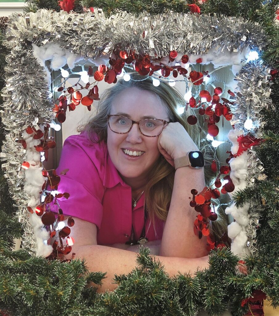 Cassie smiling through tinsel and a wreath.