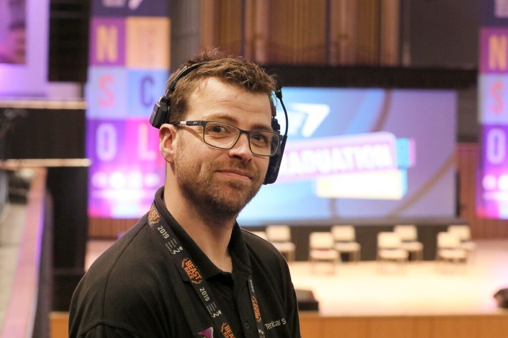 Headshot of Kevin at graduation with a headset on.