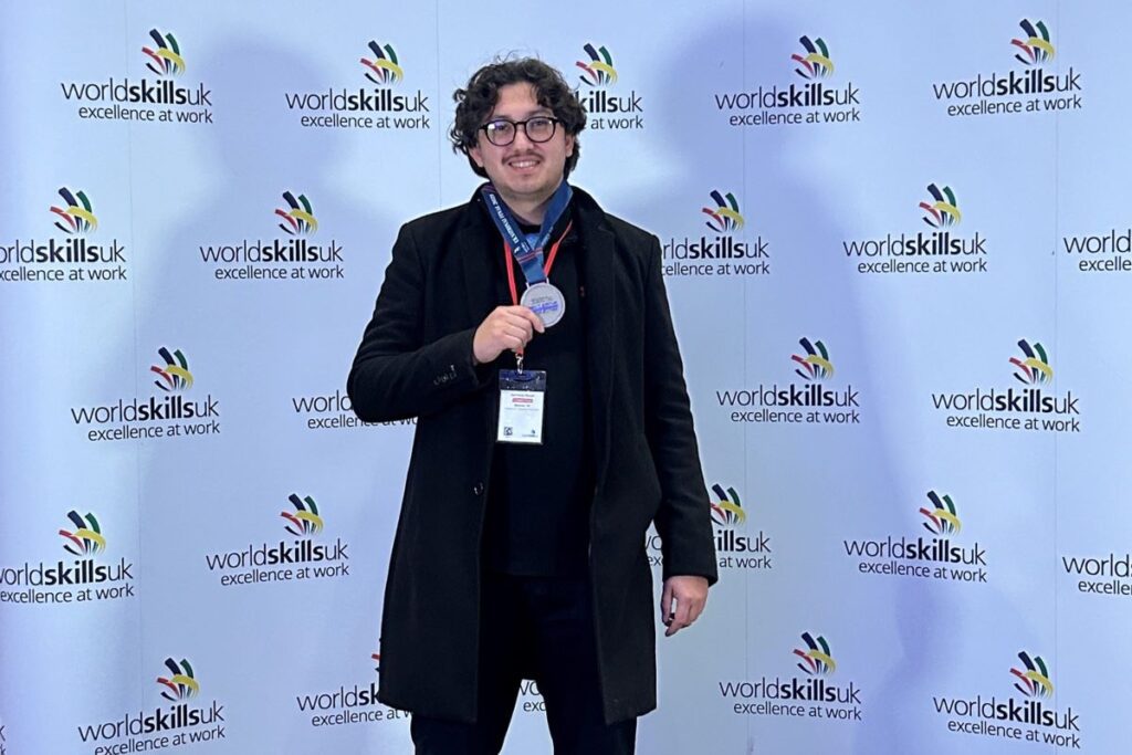 Michael holding a silver medal in front of a WorldSkills UK background.