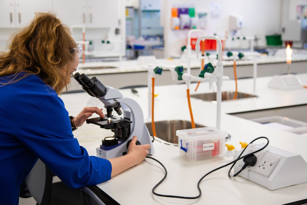 someone looking into microscope in lab