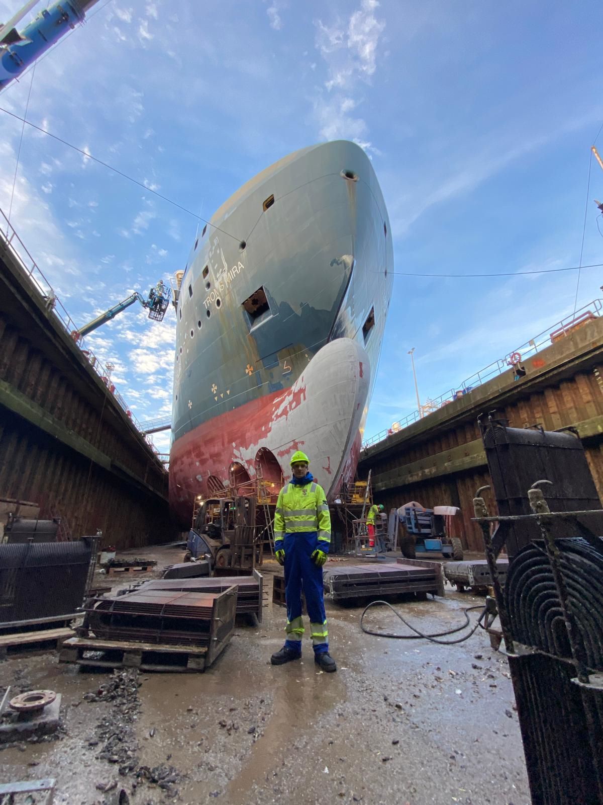 Richard standing in front of a big ship in a yard.