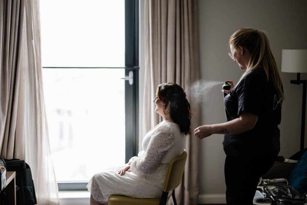 Cara spraying a client's hair with hairspray