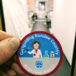 Medicine maker girlguiding badge in front of drug discovery unit lab