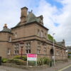 Historic sandstone building housing Brechin Library, featuring decorative architecture, turreted corners and an Angus Alive sign beside a street junction.