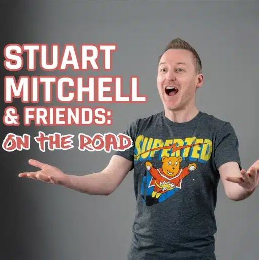 An event graphic for "Stuart Mitchell & Friends: On The Road." On the right, a man with short brown hair is pictured with an excited, open-mouthed expression and his arms outstretched. He is wearing a grey t-shirt featuring a "SuperTed" cartoon character. The event title is written in large white and red text on the left against a plain grey background.