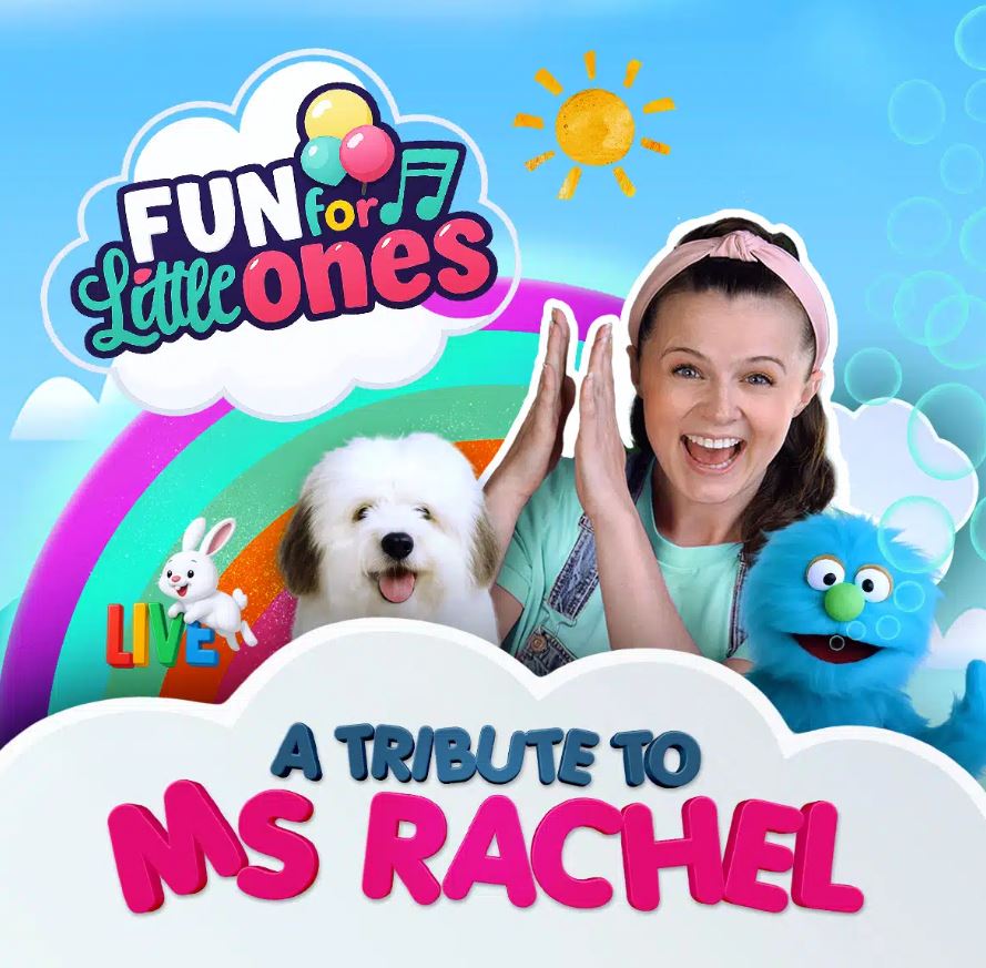 A brightly colored, animated graphic promoting a live show titled "FUN for Little Ones LIVE: A TRIBUTE TO MS RACHEL," with the main text in bold, playful fonts against a blue sky background with bubbles, clouds, and a small sun. The image features a woman, possibly the host, smiling enthusiastically with her hands raised, standing next to a fluffy white dog and a bright blue, furry puppet. A colorful rainbow spans the background, and a small animated white rabbit is shown hopping near the word "LIVE."