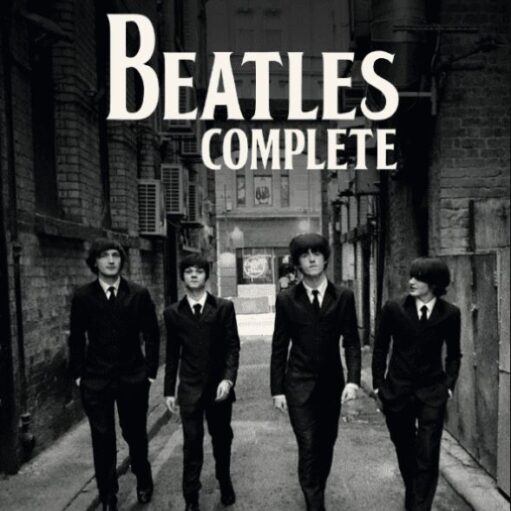 A black and white photograph of four men dressed in matching black suits and ties with mop-top haircuts, walking towards the viewer down a narrow, brick-walled alleyway. The text above reads "DIRECT FROM THEIR CAVERN CLUB RESIDENCY BEATLES COMPLETE."