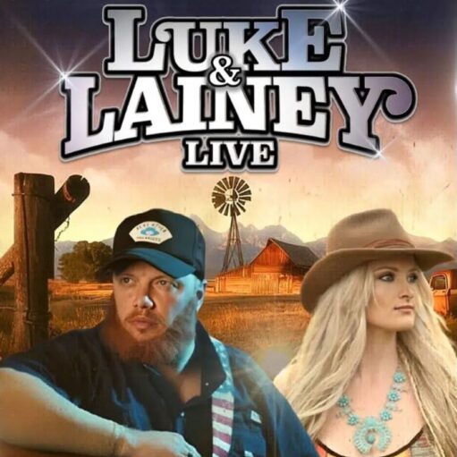 A promotional graphic for "Luke & Lainey Live" featuring two performers in front of a rural landscape. On the left is a man with a beard wearing a black baseball cap and a dark shirt. On the right is a woman with long blonde hair wearing a wide-brimmed brown hat and a turquoise necklace. The background shows a wooden fence, a windmill, a barn, and distant mountains under a warm sunset sky.