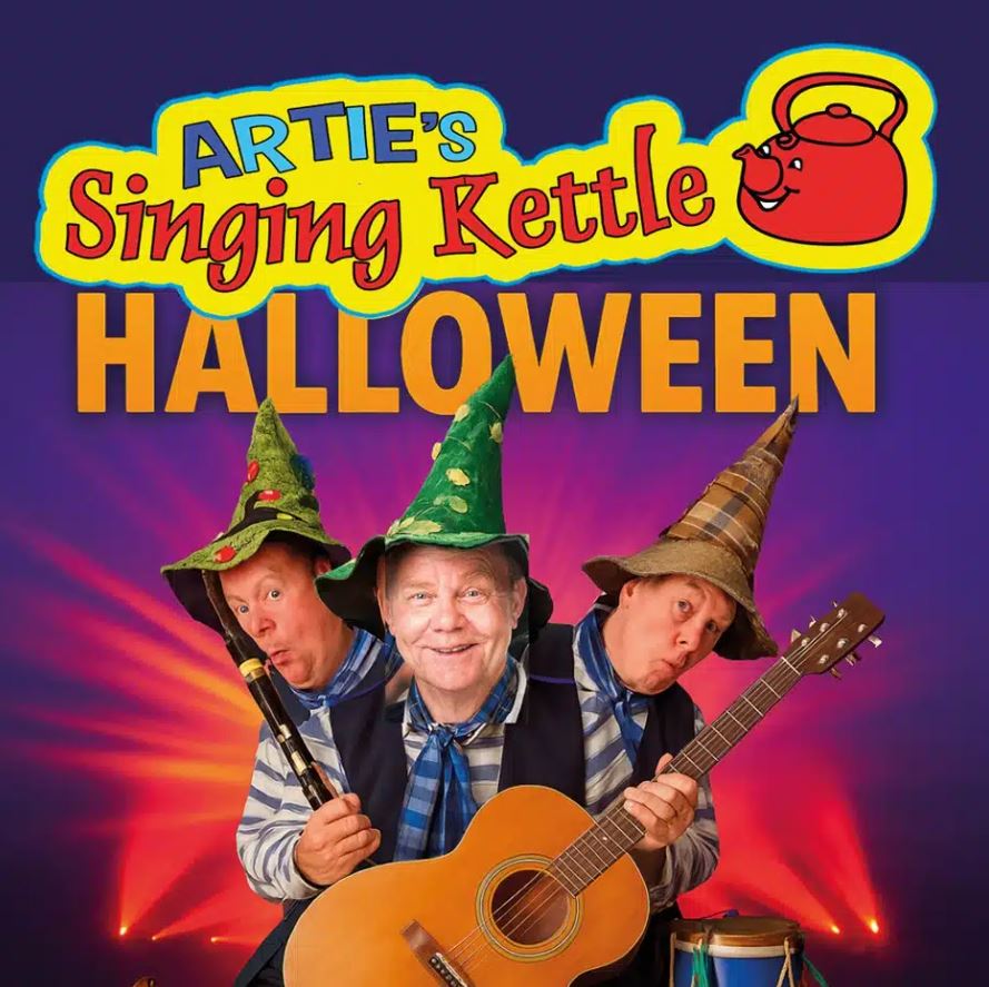 A promotional poster for "Artie's Singing Kettle Halloween" featuring three men dressed as wizards with pointed hats, one holding a guitar and another holding a flute. The background is a vibrant purple with bright lights, and the title is written in large, playful yellow and red letters.