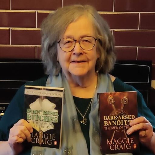 Person with grey hair and glasses holding two books by Maggie Craig in front of a tiled wall, including Damn’ Rebel Bitches: The Women of the ’45 and Bare-Arsed Banditti: The Men of the ’45.