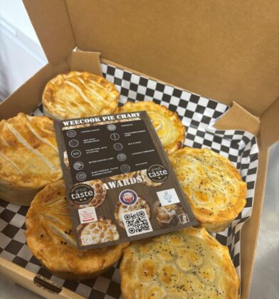 Selection of award-winning handmade pies arranged in a cardboard takeaway box, accompanied by a flavour guide card showing the different pie varieties available.