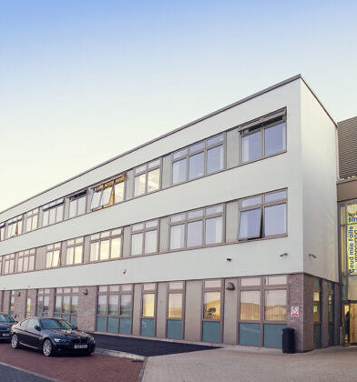 Modern multi-storey community campus building with large windows and a contemporary entrance, viewed from the surrounding car park and pedestrian area.