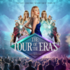 Promotional poster for The Tour of the Eras, advertised as “The UK’s Leading Taylor Swift Tribute”. The design features multiple stage-performance images of a singer in different costumes arranged around a central figure wearing a blue sequined outfit. A large audience fills the foreground of a concert arena beneath dramatic blue lighting and cloud effects. In the centre, a diamond-shaped graphic displays the title The Tour of the Eras, with smaller text below reading “Starring Hannah Jenkins”. The poster uses bright blue, purple and silver tones to create a large-scale concert atmosphere.