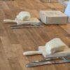 A pasta-making workshop setup is arranged on a wooden floor, with portions of dough wrapped in cling film placed on small wooden gnocchi boards beside knives and forks. Cardboard boxes and display cards for The Fife Pasta Company are positioned nearby, indicating an organised hands-on food activity. The simple layout highlights the ingredients and tools used in fresh pasta making, creating a welcoming environment for participants to learn traditional pasta-making techniques.