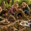 Children play outdoors in a woodland setting surrounded by natural crafts, a small wooden stick shelter, an owl perched on a stump, and a hedgehog walking on the forest floor.